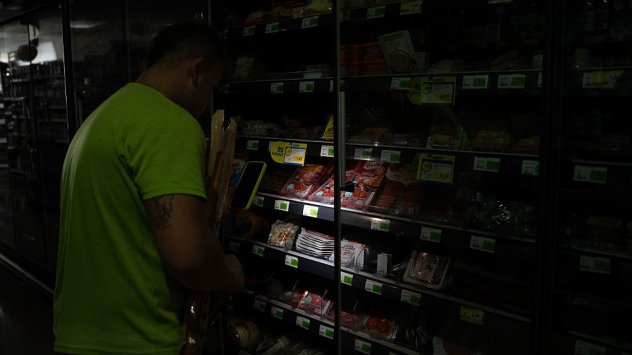 Клиент разглежда стоки в супермаркет, използвайки фенерчето на смартфон, в Тремп, Испания, на 28 април, Снимка: Bloomberg LP