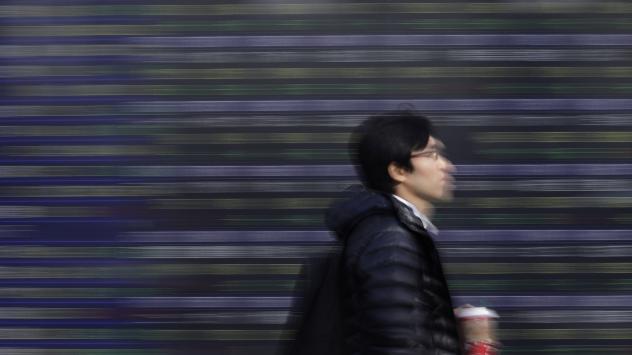 Пешеходец върви покрай панел с индекси в Япония Снимка: Kiyoshi Ota/Bloomberg