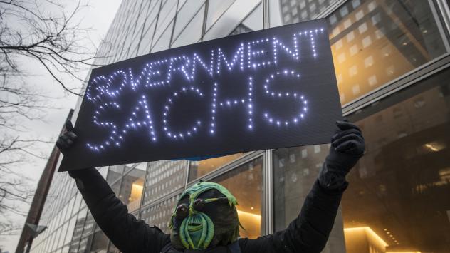 Протестиращ държи надпис, иронизиращ името на Goldman Sachs по време на митинг пред централата на компанията в Ню Йорк Снимка: Victor J. Blue/Bloomberg