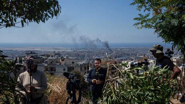 Журналисти правят репортаж от наблюдателен пункт, докато димът се издига от района Дахиех в Бейрут след израелски въздушен удар на 5 октомври. Снимка: Карл Корт/Getty Images