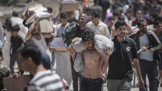 Палестинци пренасят хуманитарна помощ, събрана от разпределителен център в коридора Нецарим, централната част на Ивицата Газа, на 29 май. Снимка: Bloomberg LP