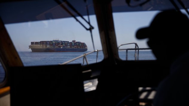 Капитанът на пристанищна моторна лодка се приближава към контейнеровоз в пристанището на Лос Анджелис. Снимка: Патрик Т. Фалън/Bloomberg