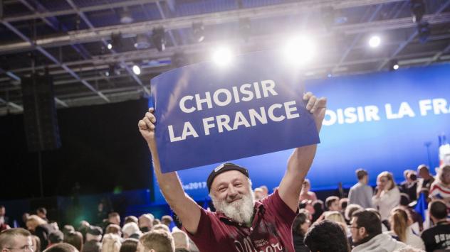Участник в митинг на Националния фронт държи плакат с надпис &quot;Да изберем Франция&quot;. Вилпент, Франция. 1 май 2017. Photographer: Marlene Awaad/Bloomberg