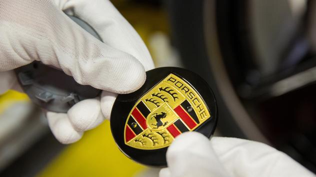 Работник държи емблемата на Порше Снимка: Krisztian Bocsi/Bloomberg