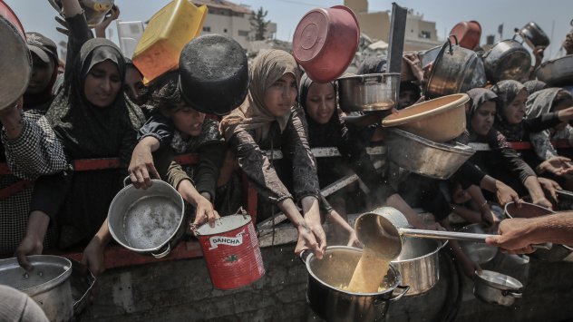 Палестинци държат паници, за да получат храна от благотворителен пункт за раздаване на храна в град Газа, на 25 юли. Фотограф: Ахмад Салем/Bloomberg