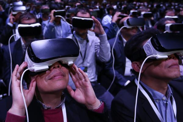 &lt;p&gt;Делегати на Мобилния световен конгрес в Барселона изпробват шлемовете на Gear VR (virtual reality), произведени от Samsung Electronics Co. на събитието Samsung Unpacked, в навечерието на Mobile World Congress в Барселона, Испания на 21 февруари 2016.&lt;/p&gt;

&lt;p&gt;Photographer: Chris Ratcliffe/Bloomberg&lt;/p&gt;
