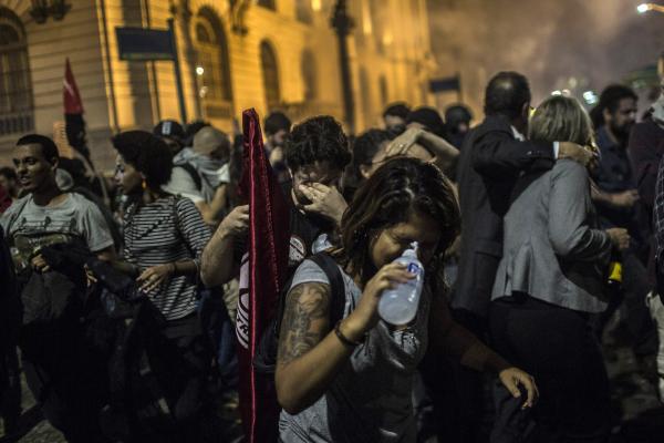 <p>Разпръскване на демонстрация за оставката на президента Темер със сълзотворен газ. Рио де Жанейро, Бразилия. 18 май 2017. Photographer: Dado Galdieri/Bloomberg.<br />
Опитът на Темер да отхвърли обвиненията не успяха да убедят мнозина през уикенда. Важен коалиционен съюзник &ndash; партията на бразилските социалисти, го напусна и се включи към призивите на опозицията за оставка. Влиятелната правна организация OAB гласува за започване на процедура по импийчмънт.</p>
